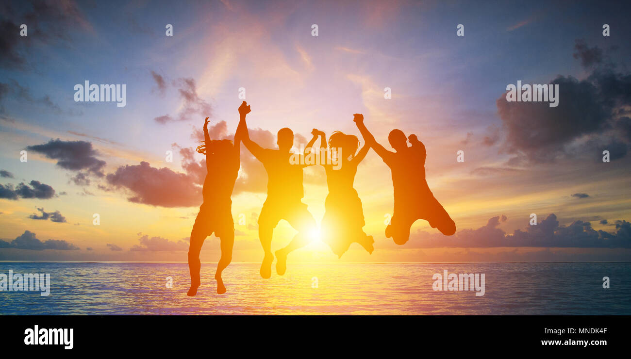 Silhouette di happy business team rendendo le mani alte nel Cielo di tramonto sullo sfondo Foto Stock