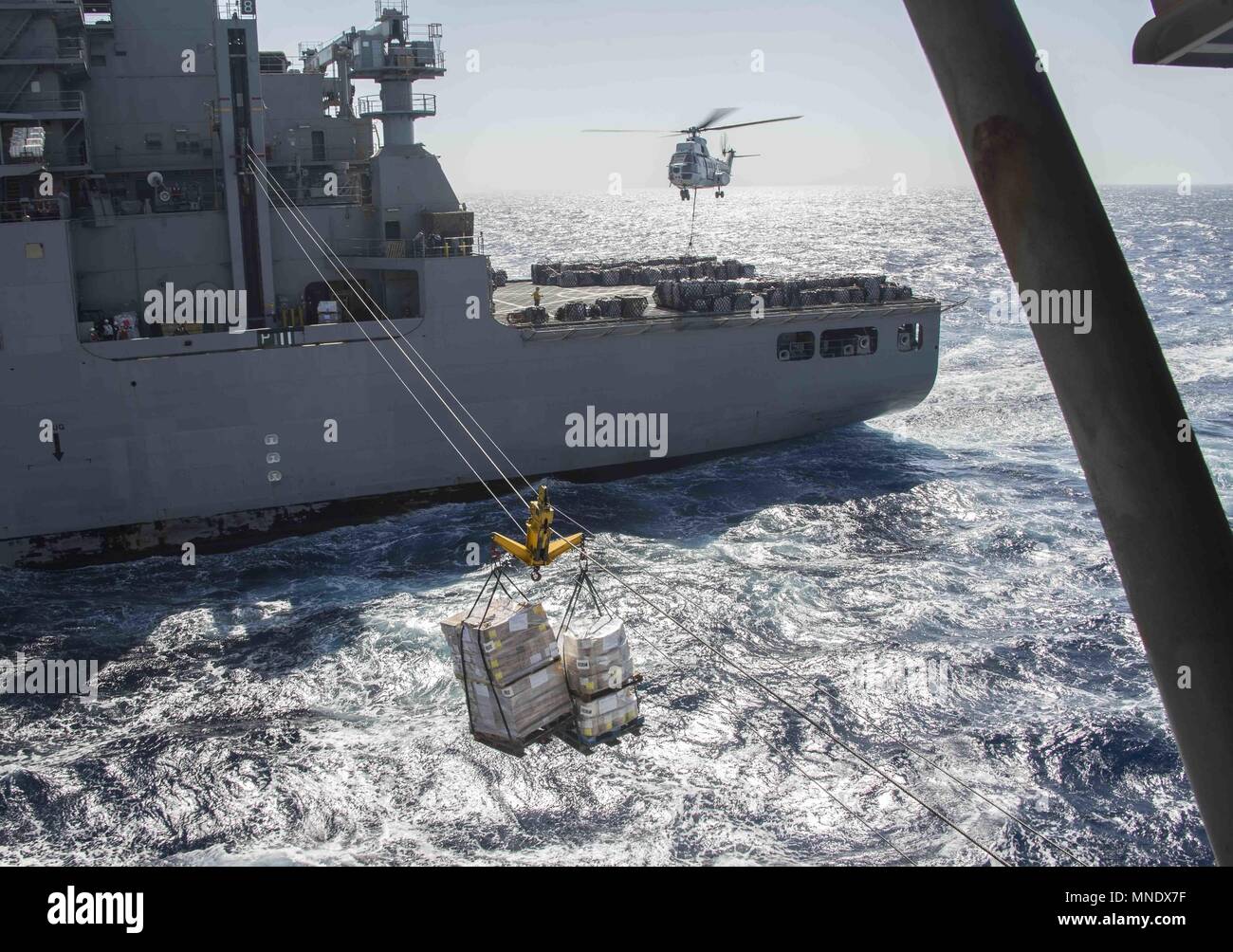 180515-N-AH771-0244 U.S. 5TH FLOTTA AREA DI OPERAZIONI (15 maggio 2018) Il trasporto di carichi secchi e munizioni nave USNS Amelia Earhart (T-AKE 6) invia i pallet di forniture per il Wasp-classe assalto anfibio nave USS Iwo Jima (LHD 7) durante un rifornimento in mare, 15 maggio 2018, 15 maggio 2018. Iwo Jima, homeported a Mayport, Fla. è sulla distribuzione per gli Stati Uniti Quinta Flotta area di operazioni a sostegno della sicurezza marittima operazioni per rassicurare gli alleati e partner e preservare la libertà di navigazione e il libero flusso di commercio nella regione. (U.S. Foto di Marina di Massa lo specialista di comunicazione di terza classe Dan Foto Stock