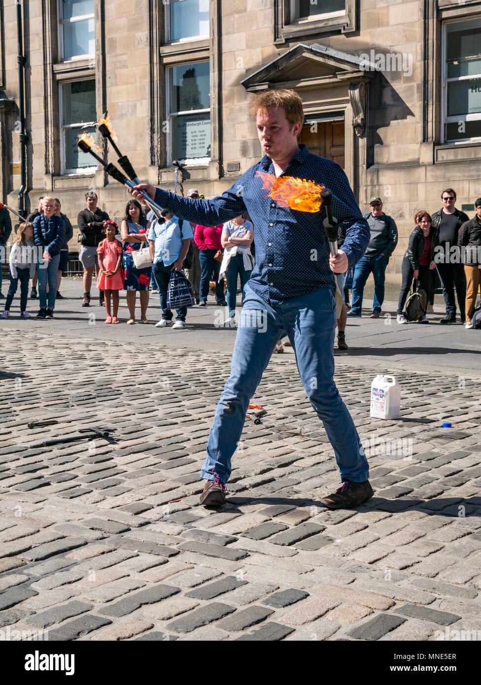 Royal Mile, Edimburgo, 16th Maggio 2018. Turisti che godono del sole e dello spettacolo di strada sul Royal Mile, Edimburgo, Scozia, Regno Unito. I turisti guardano un esecutore di strada chiamato Daniel, il cui atto include torce di giocoleria e grandi coltelli e machete Foto Stock