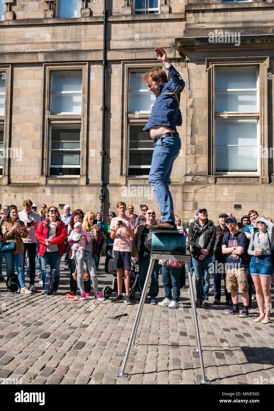 Royal Mile, Edimburgo, 16th Maggio 2018. Turisti che godono del sole e dello spettacolo di strada sul Royal Mile, Edimburgo, Scozia, Regno Unito. I turisti guardano un esecutore di strada chiamato Daniel, il cui atto include torce di giocoleria e grandi coltelli e machete Foto Stock