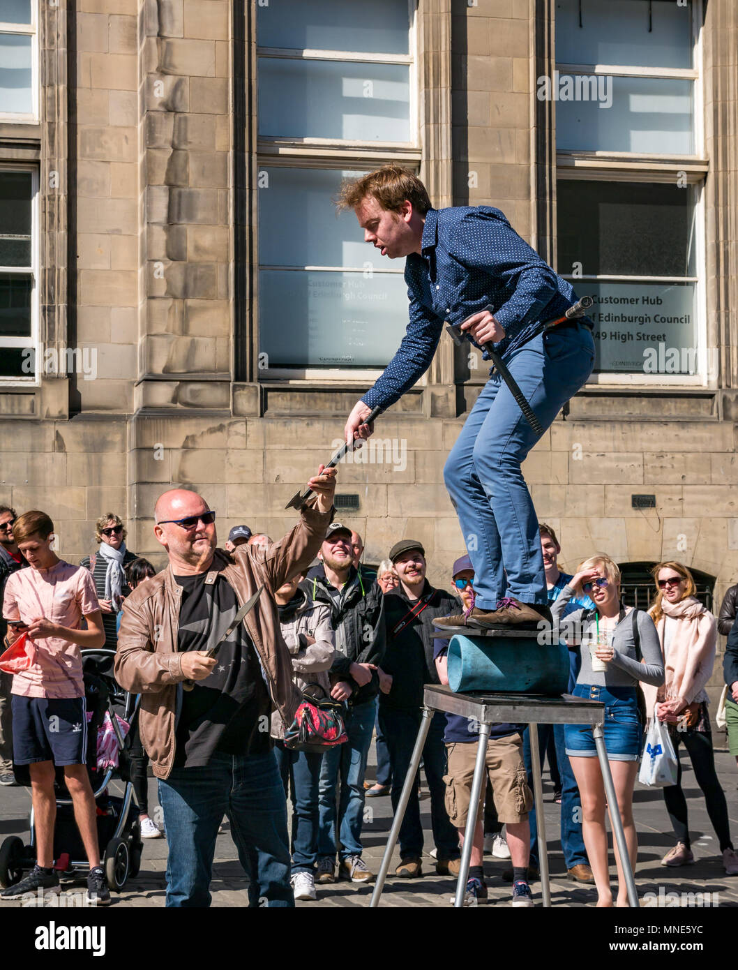 Royal Mile, Edimburgo, 16th Maggio 2018. Turisti che godono del sole e dello spettacolo di strada sul Royal Mile, Edimburgo, Scozia, Regno Unito. I turisti guardano un esecutore di strada chiamato Daniel, il cui atto include torce di giocoleria e grandi coltelli e machete Foto Stock