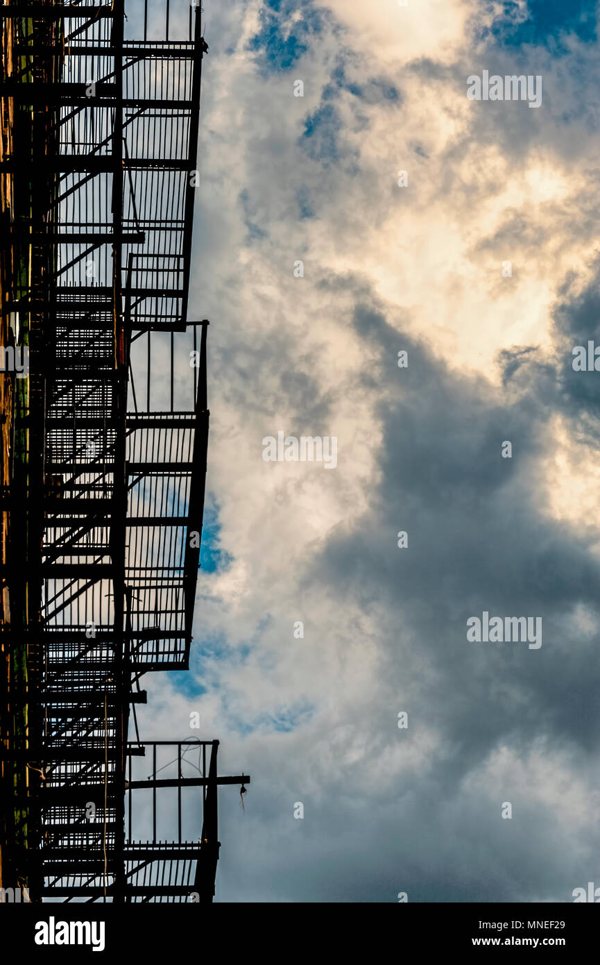 Abstract di silhouette fire escape sul lato dell'edificio e cielo nuvoloso Foto Stock