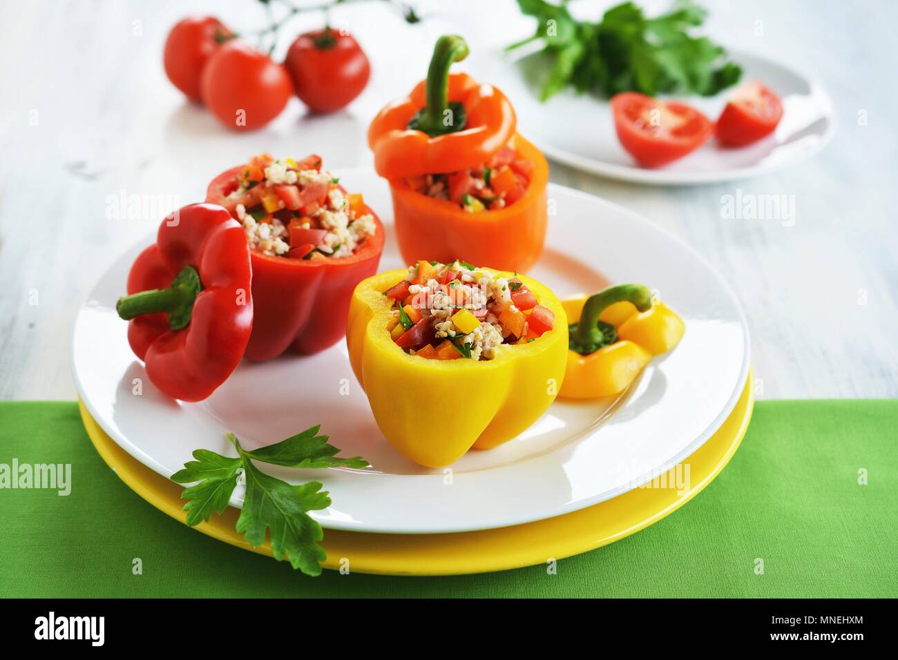 Rosso, giallo e arancione peperoni riempiti con un riso, pepe e insalata di pomodoro Foto Stock