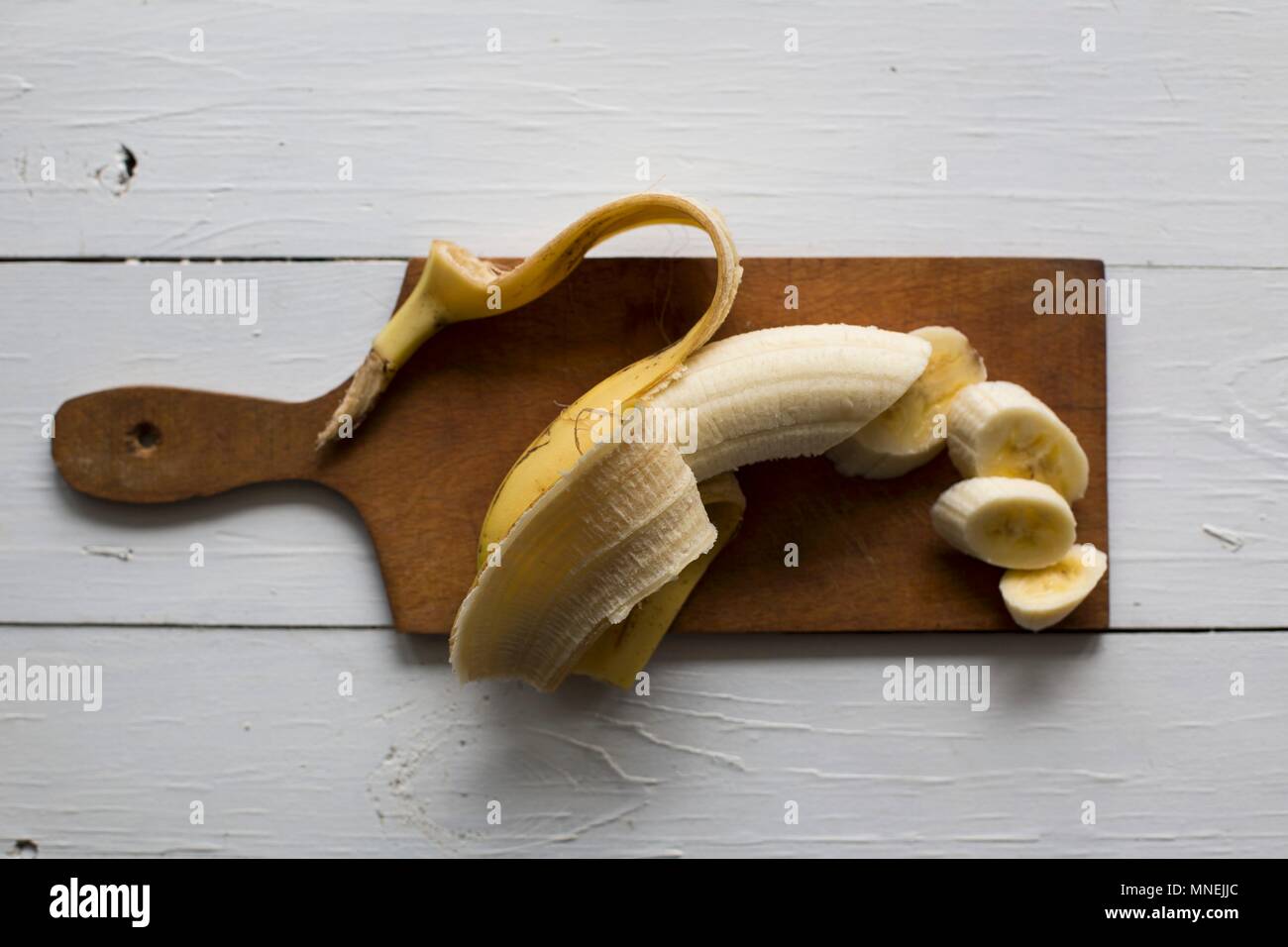 Una banana su un tagliere di legno Foto Stock