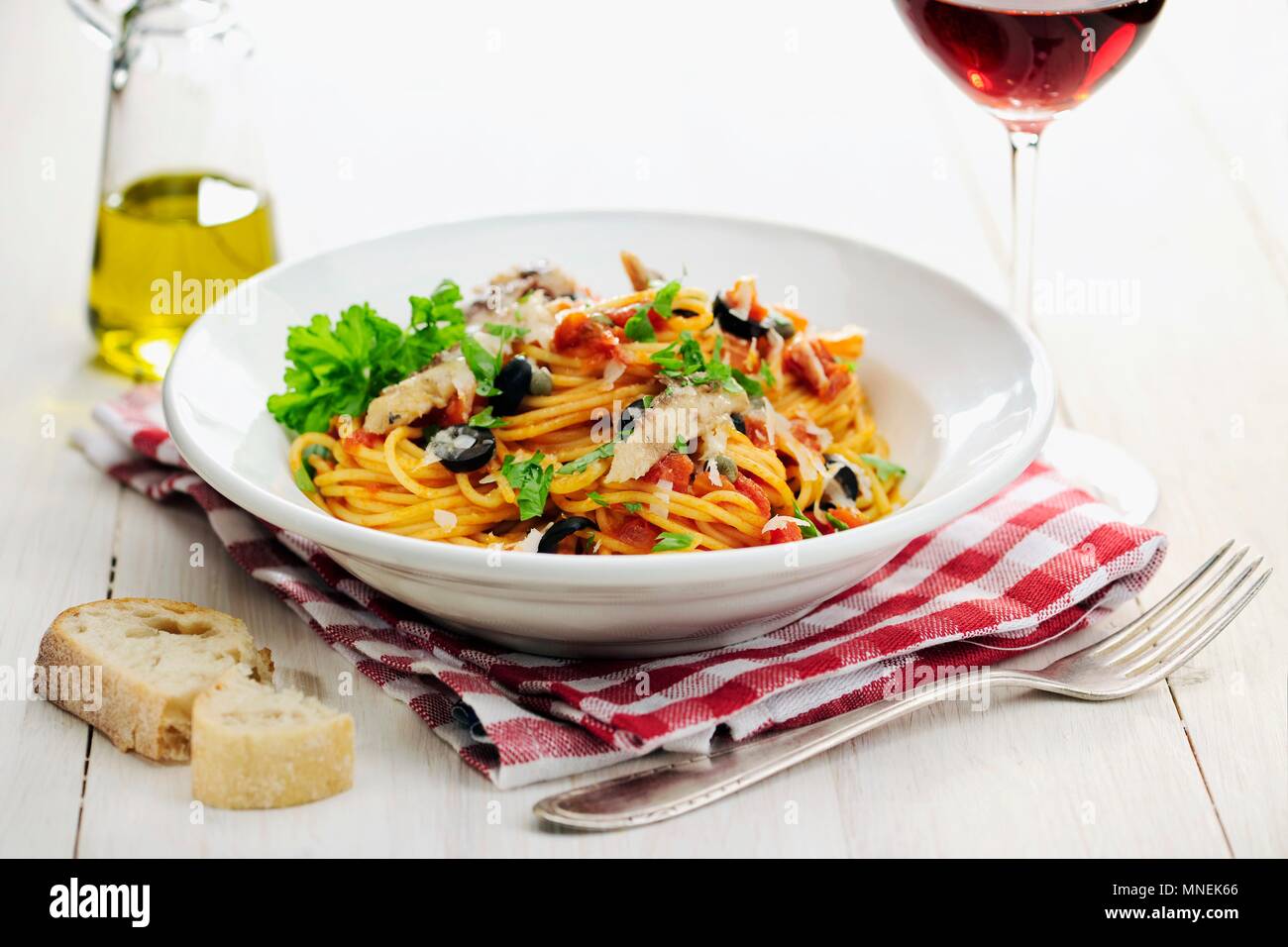 Spaghetti Puttanesca, sugo di pomodoro fatta con cipolle, capperi, olive nere e le acciughe; messa a fuoco selettiva Foto Stock