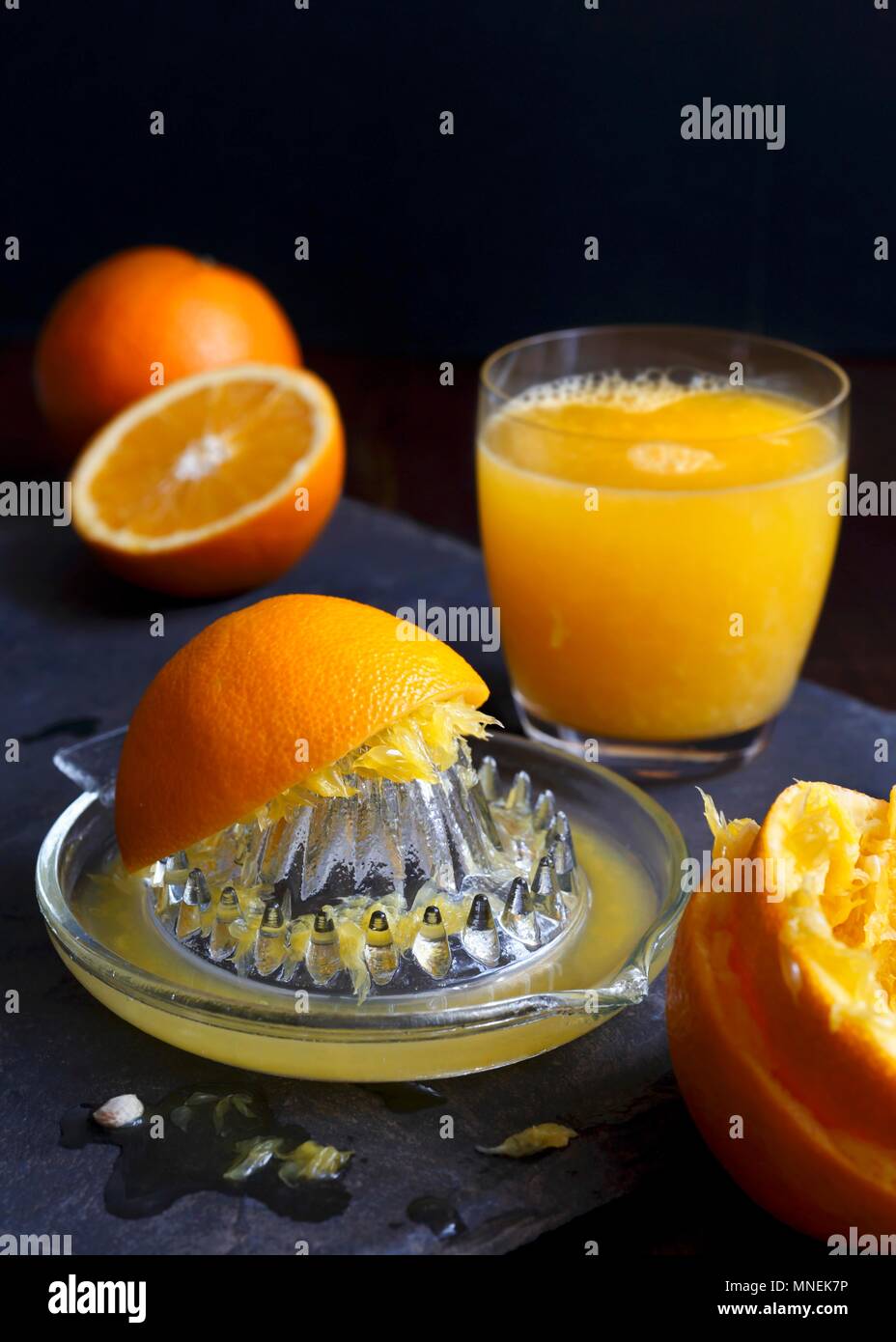 Vetro manuale juicet estrattore con spremuta di arance e un bicchiere di  succo di arancia su una di ardesia scura Foto stock - Alamy