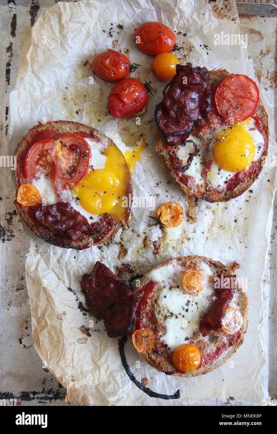 Pane tostato con pancetta, pomodori e uova fritte per la prima colazione Foto Stock