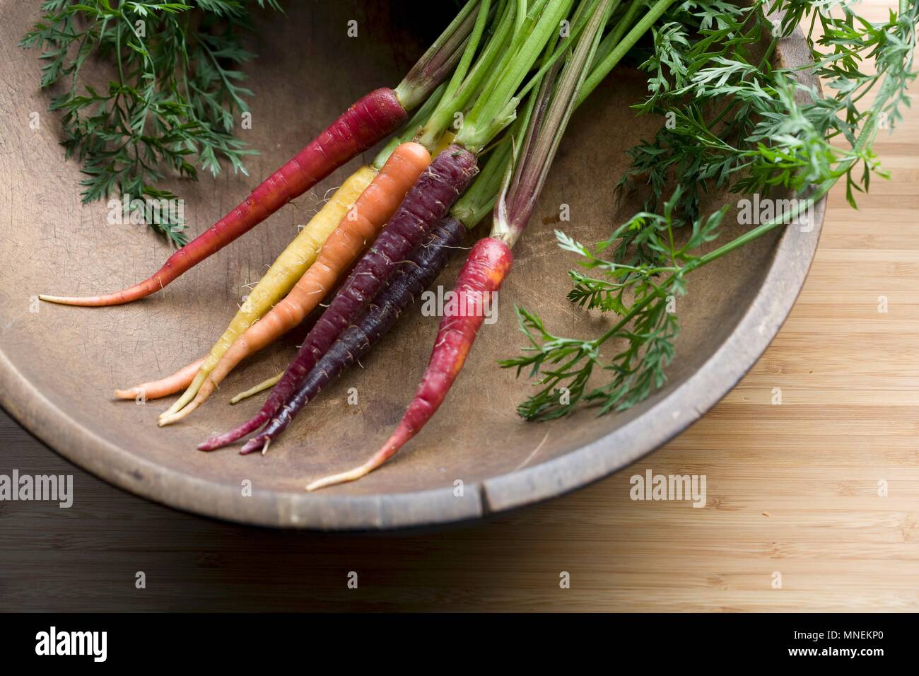 Rainbow carote in una vecchia ciotola di legno Foto Stock
