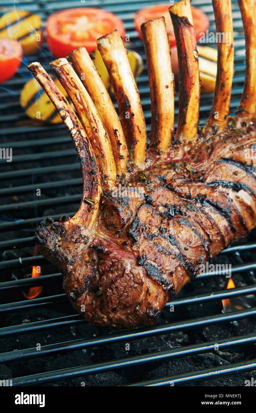 Una cremagliera di agnello con erbe e vino di porto su un grill rack Foto Stock