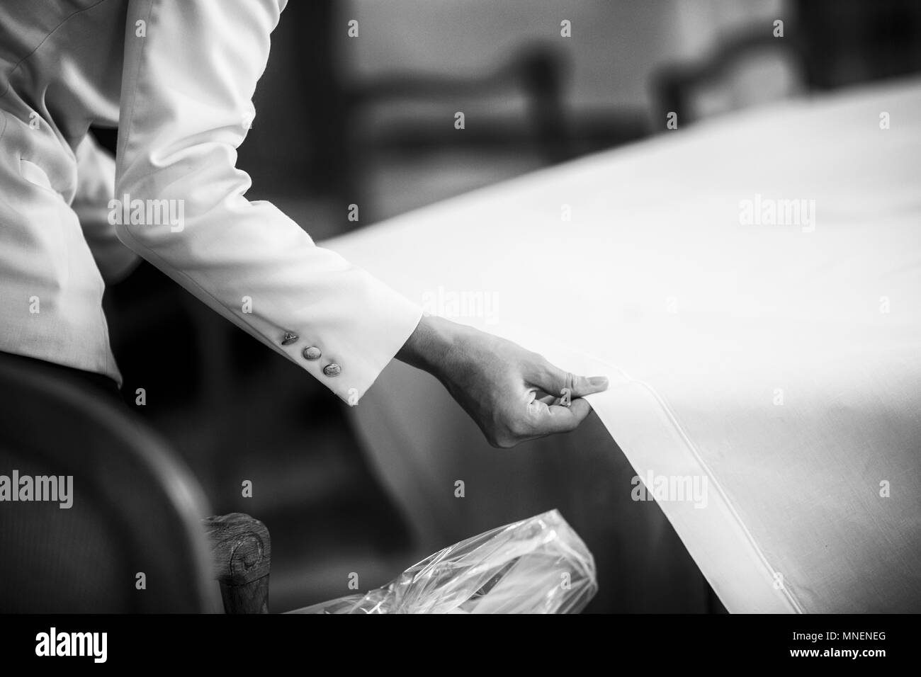 Un cameriere tirando una tovaglia su un tavolo ristorante Foto Stock