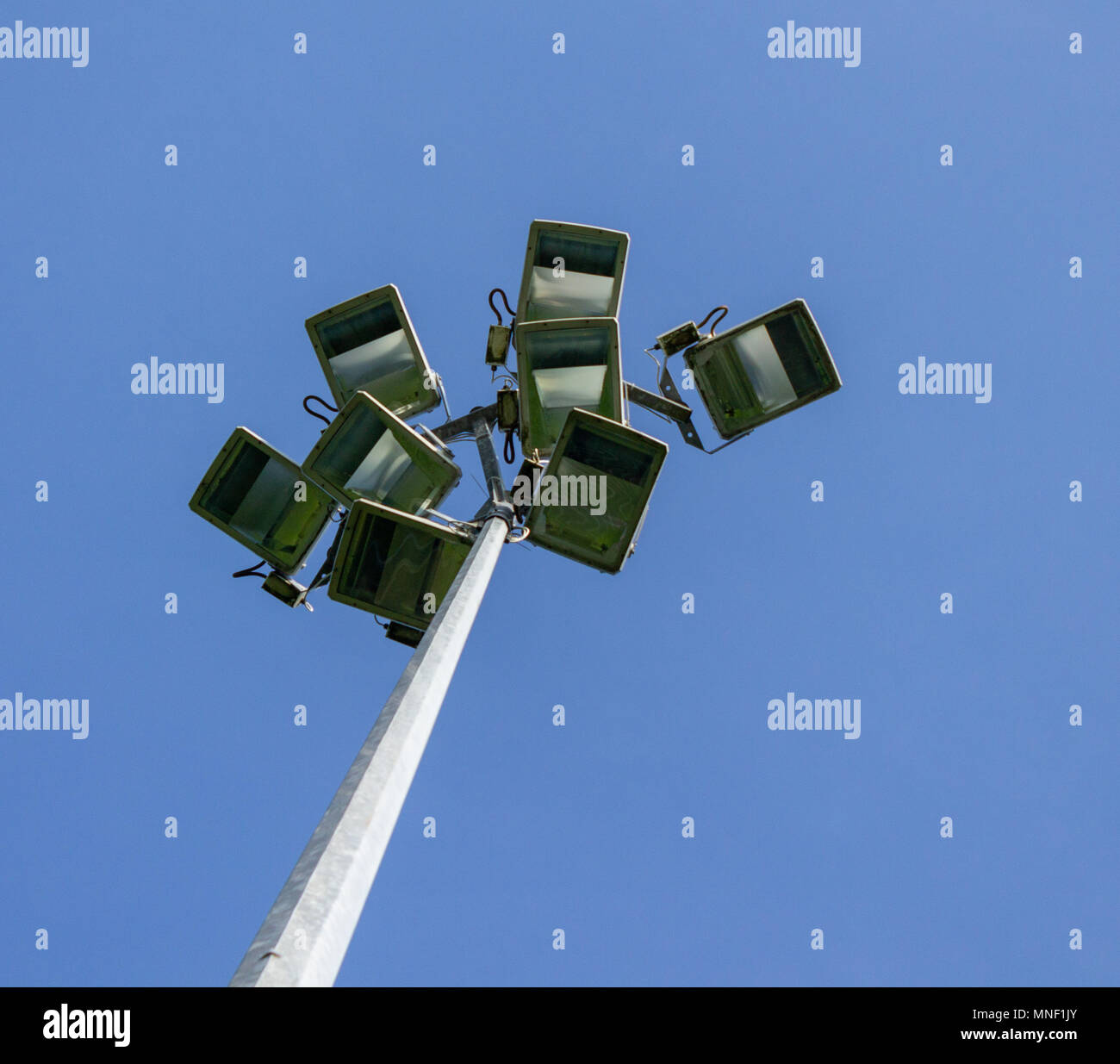 Fari di lavoro non acceso in corrispondenza di un campo sportivo stagliano contro un cielo blu chiaro Foto Stock