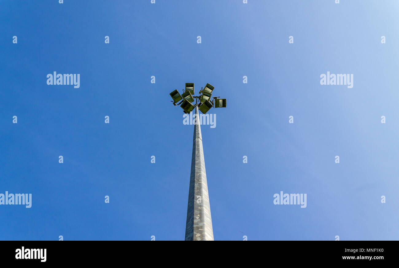 Fari di lavoro non acceso in corrispondenza di un campo sportivo stagliano contro un cielo blu chiaro Foto Stock