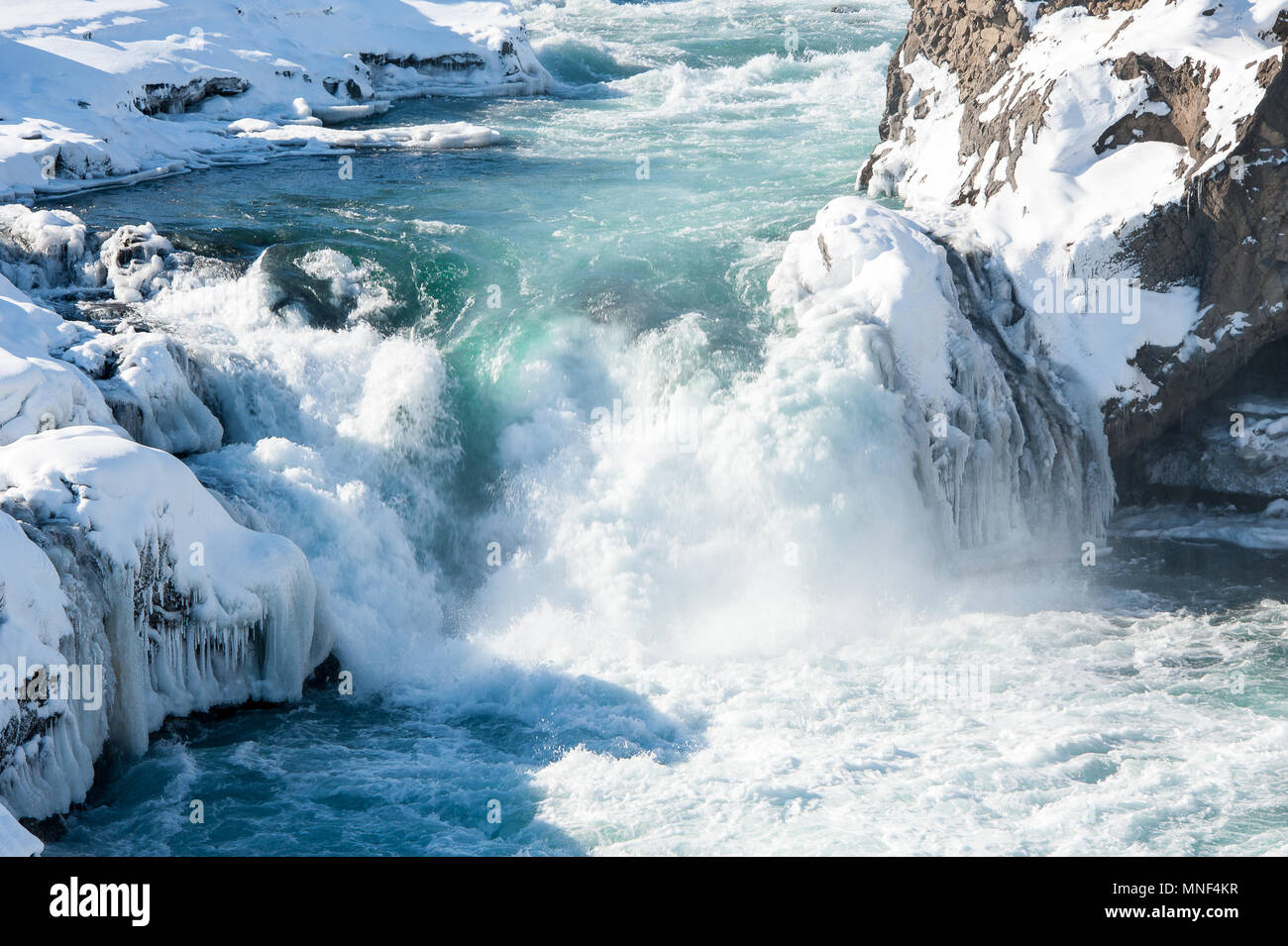 Acque selvagge di Skjalfandafljot fiume che scorre nelle cascate Godafoss. Agitando l'acqua turchese, innevato paesaggio congelato, contesto roccioso Foto Stock