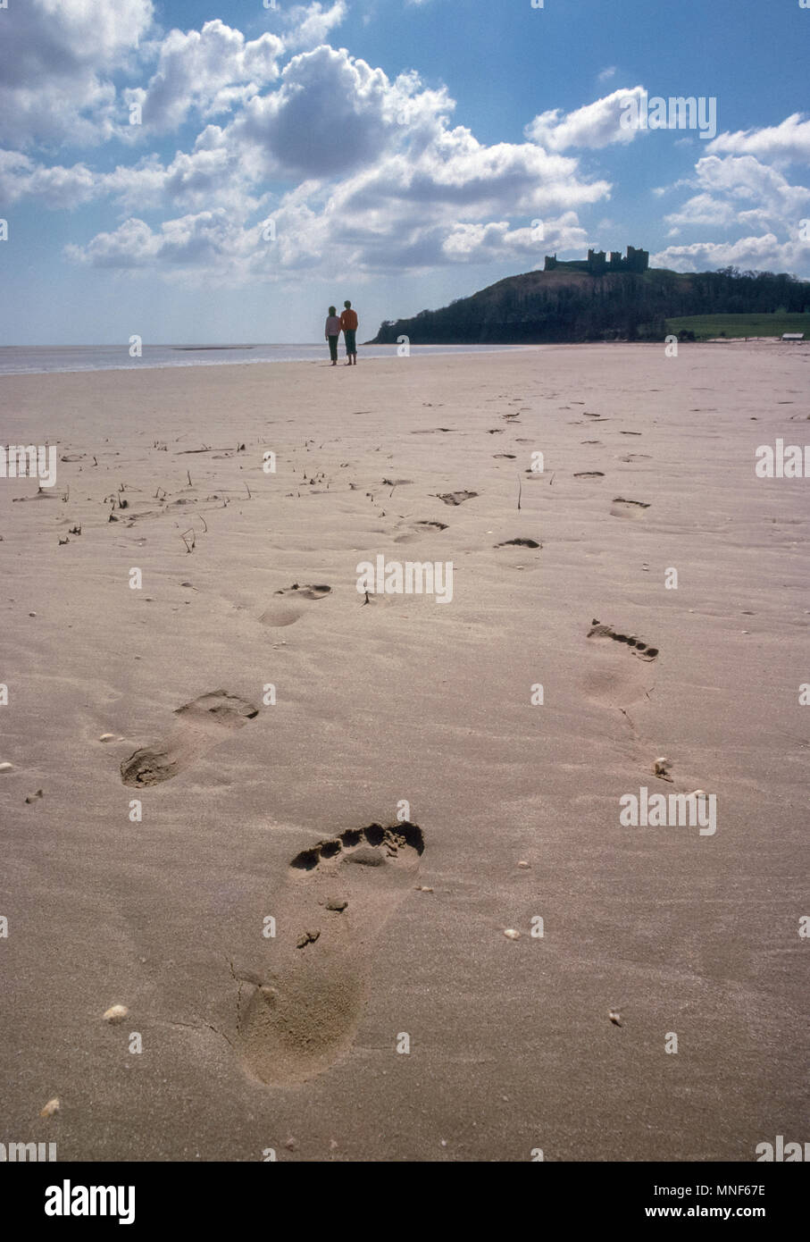 Coppia giovane per passeggiare sulla spiaggia deserta di fronte Llanstephan Castello, Carmarthenshire Wales UK Foto Stock