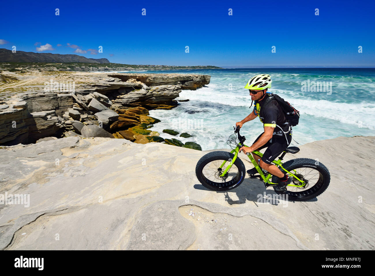 Mountain biker con Fatbike sulla scogliera, tour in bici a morire Plaat Beach, riserva, De Kelders, Gansbaai, Western Cape Foto Stock