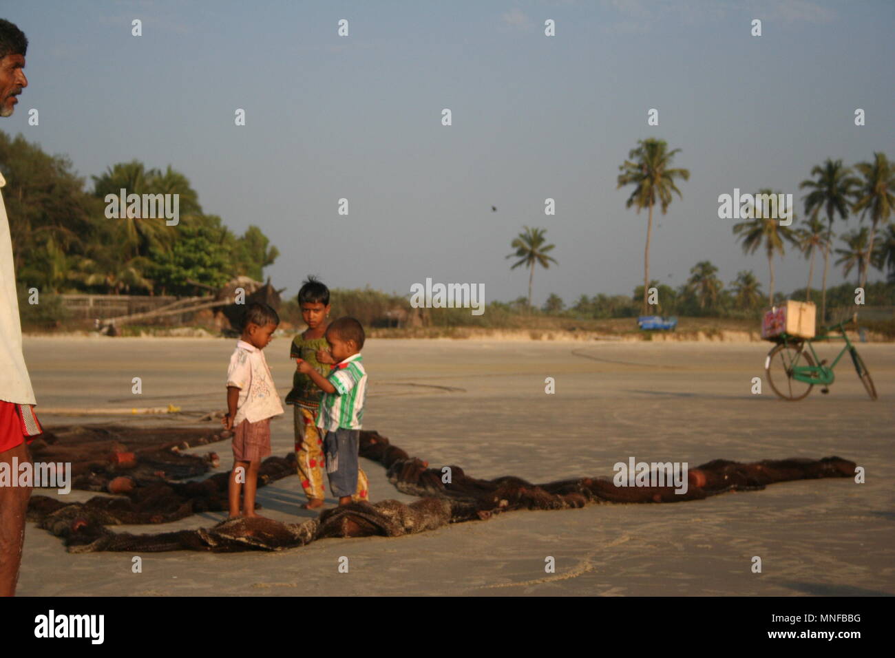 Bambini indiani, rete da pesca e gelato Bike sulla spiaggia di Colva, India Foto Stock