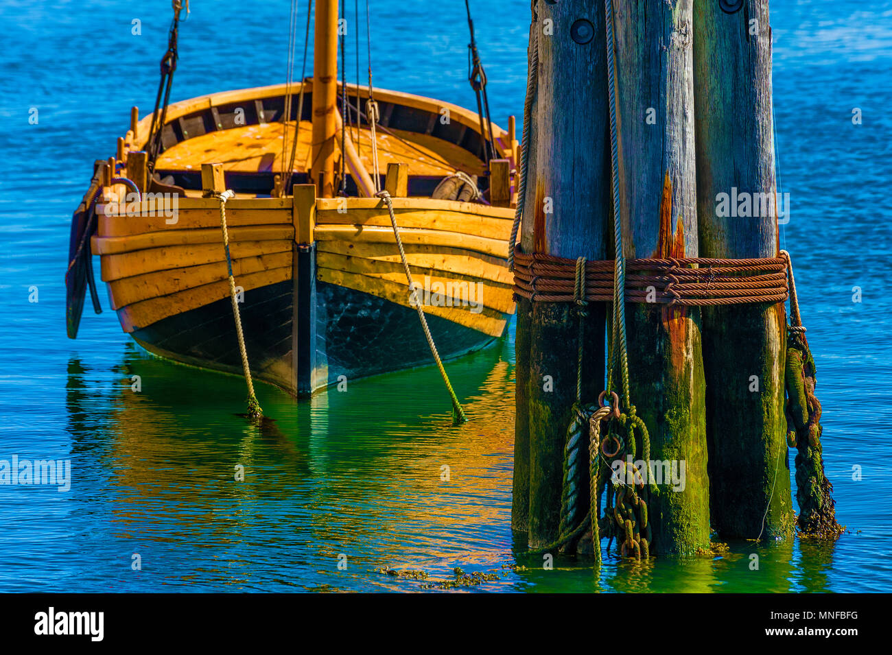 Plymouth, Massachusetts, STATI UNITI D'America - 13 settembre 2016 Pilions sit in acqua vicino ad un ancoraggio dinghy in legno che è una replica di uno i pellegrini utilizzato. Foto Stock