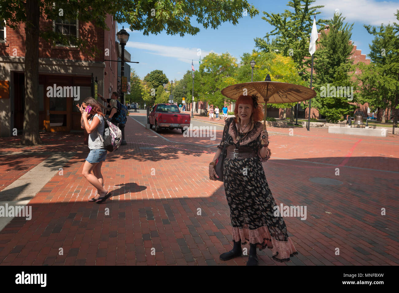 Salem, Massachusetts, STATI UNITI D'America - 14 Settembre 2016: un locale commerciale donna pone per la telecamera mentre lei stessa sfumatura dal sole con la sua parasol mentre su di lui Foto Stock