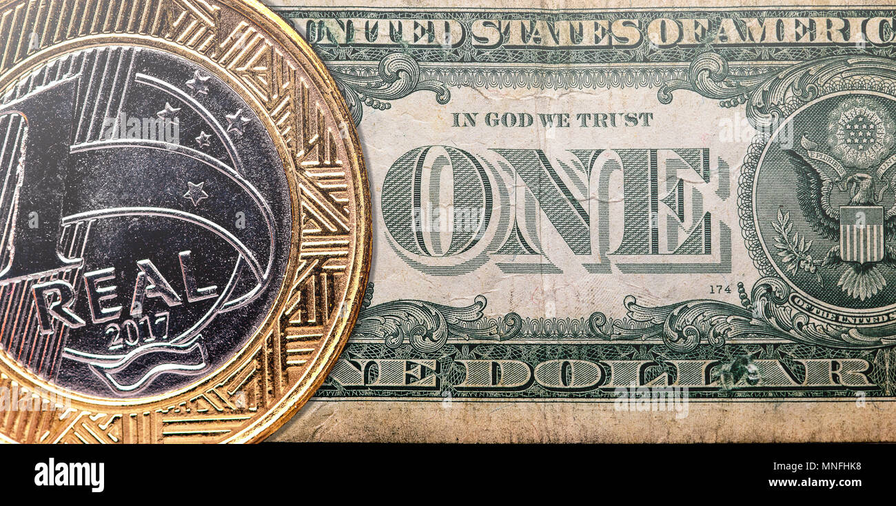 Un Real brasiliano coin overlaped su un US Dollaro americano Bill, tasso di cambio e il concetto di economia idea Foto Stock