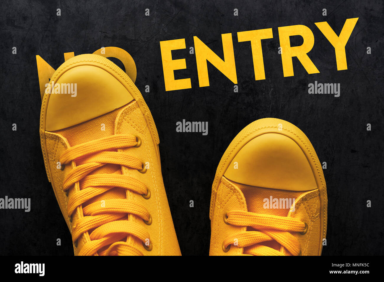 Giovane ribelle persona in piedi su nessuna voce segno, vista dall'alto di sneakers giallo sul pavimento in calcestruzzo Foto Stock