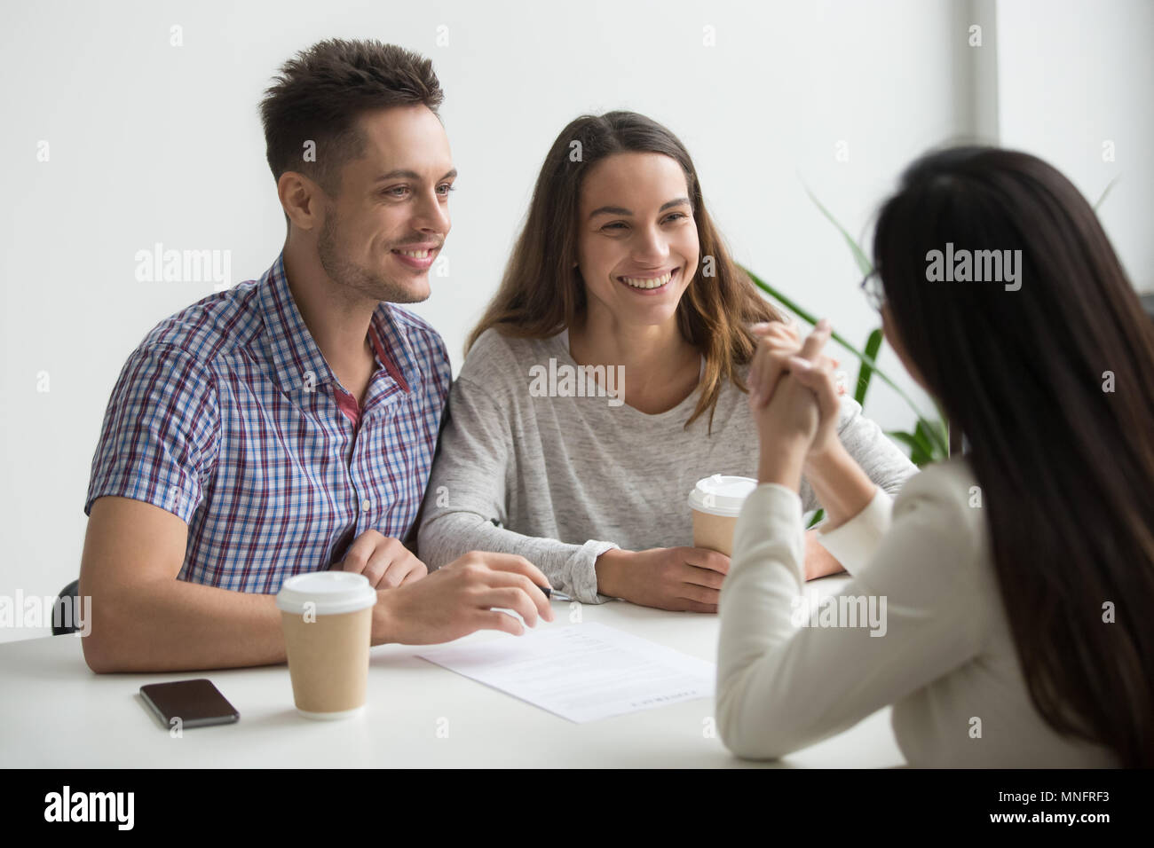 Coppia sorridente parlando di agente immobiliare Foto Stock
