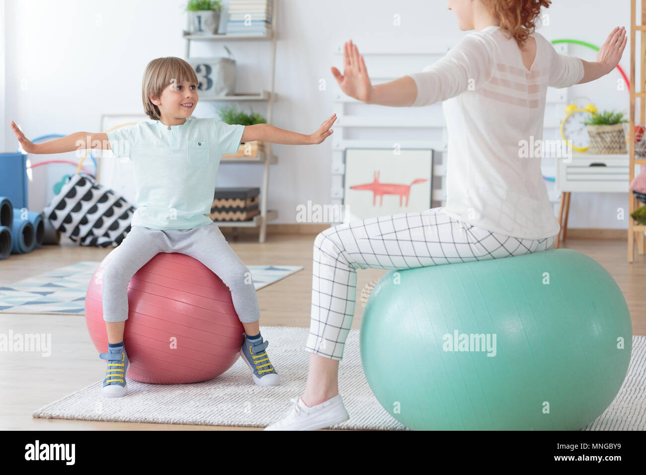 Fisioterapista e giovane ragazzo facendo stretching esercizio sulle coloratissime palle in sala luminosa Foto Stock
