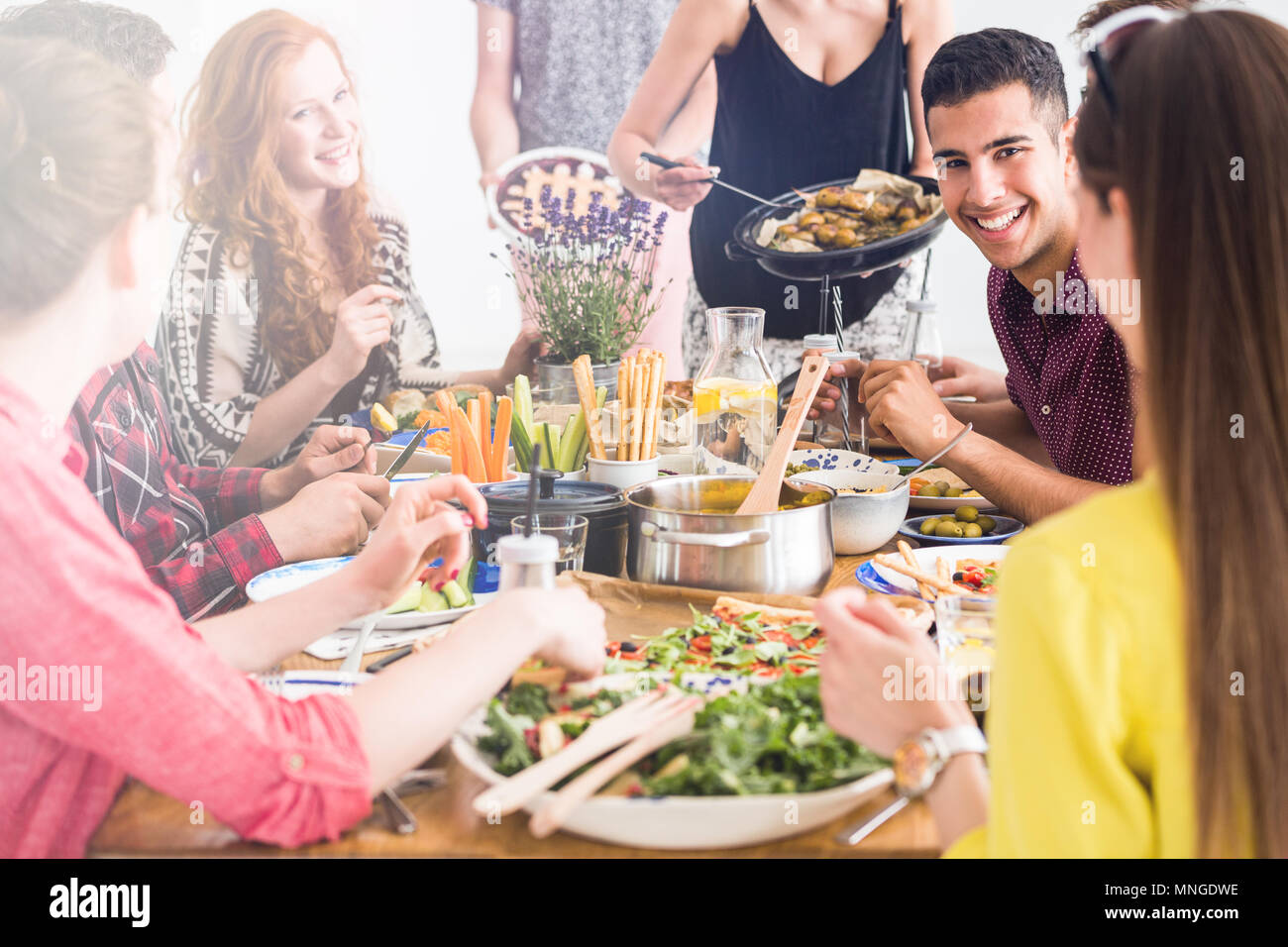 Le persone felici cucinare e mangiare insieme vege pranzo fresco a amico Foto Stock