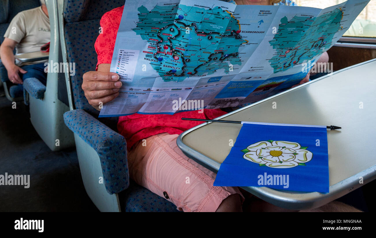 I passeggeri di un treno guardando il Tour de Yorkshire mappa con un Yorkshire rosa bianca bandiera. Foto Stock