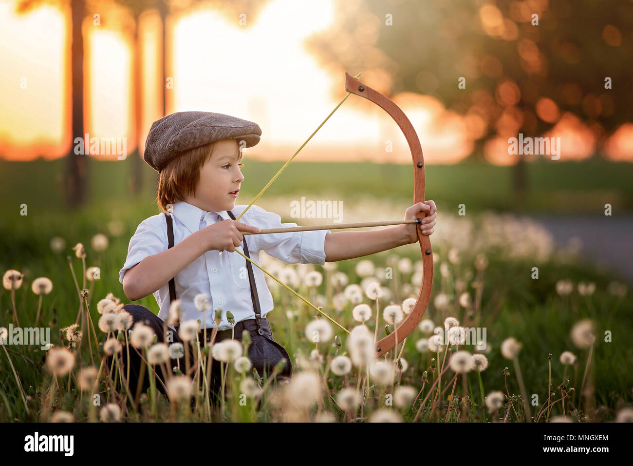Ritratto di bambino che gioca con arco e frecce, tiro con l'arco spara una  prua al bersaglio sul tramonto Foto stock - Alamy