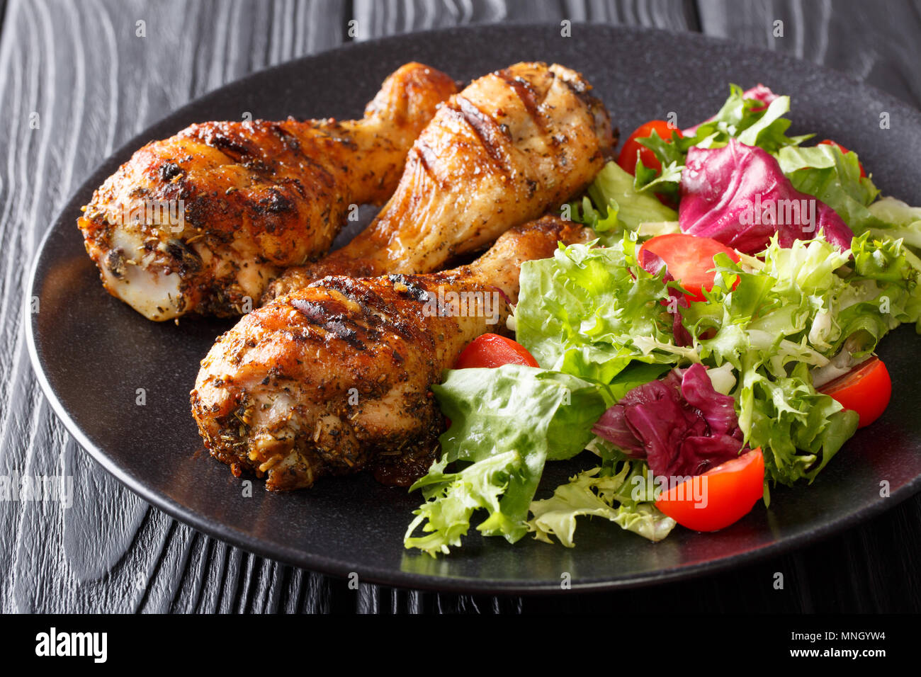 Pollo alla griglia cosce di pollo disossate e verdure fresche su sfondo nero in primo piano orizzontale. Foto Stock