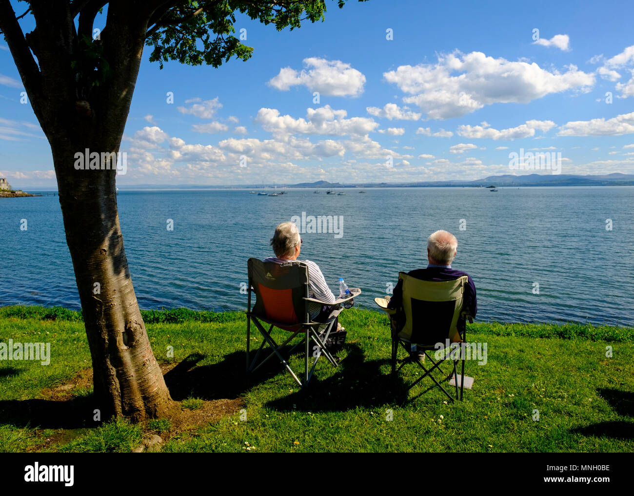 Coppia senior godono di vista del Firth of Forth a Aberdour villaggio in Fife, Scozia, Regno Unito Foto Stock
