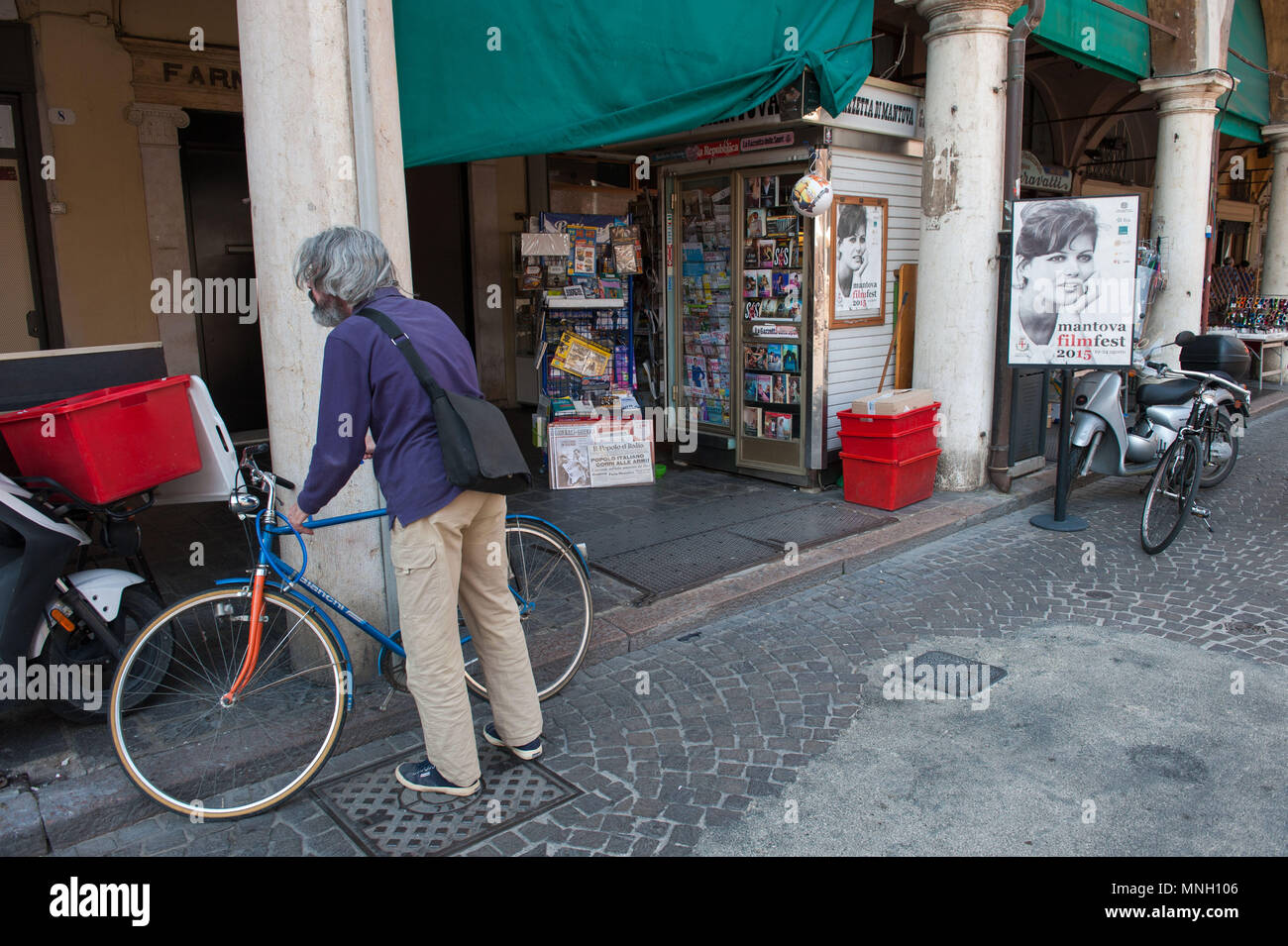 Mantova, l'uomo con una bici in prossimità di un newskiosk esponendo un poster di italiano attrice Claudia Cardinale. L'Italia. Foto Stock