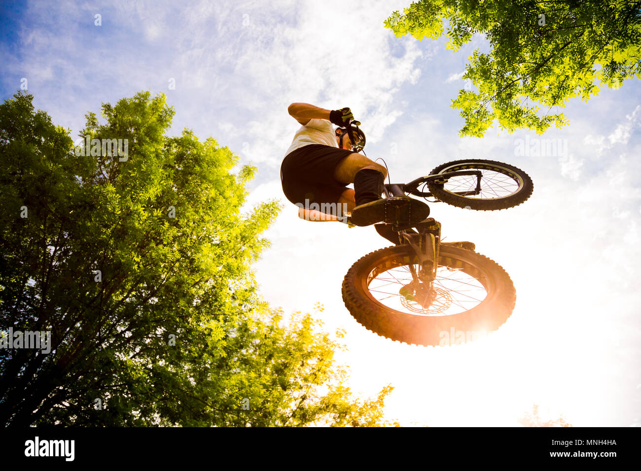 Giovane ciclista volare con la sua prova bici nella foresta al tramonto. Extreme a basso angolo di visione Foto Stock