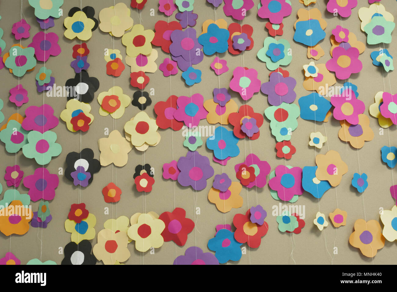 Carta colorata germoglio di fiore di ghirlande, posto su una parete, che sono state fatte dai bambini Foto Stock