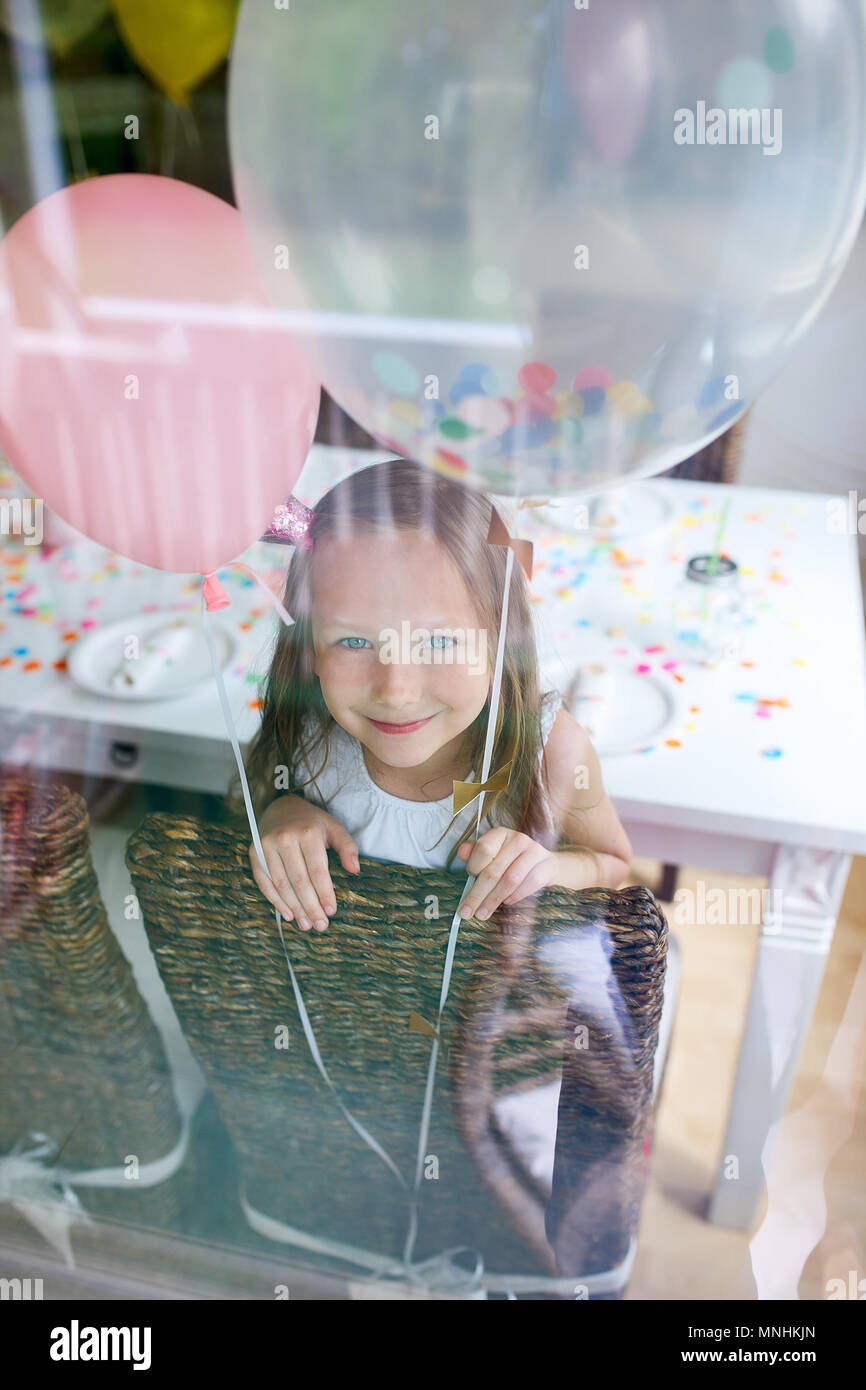 Adorabile bambina con palloncini colorati a bambini festa di compleanno di guardare attraverso una finestra Foto Stock