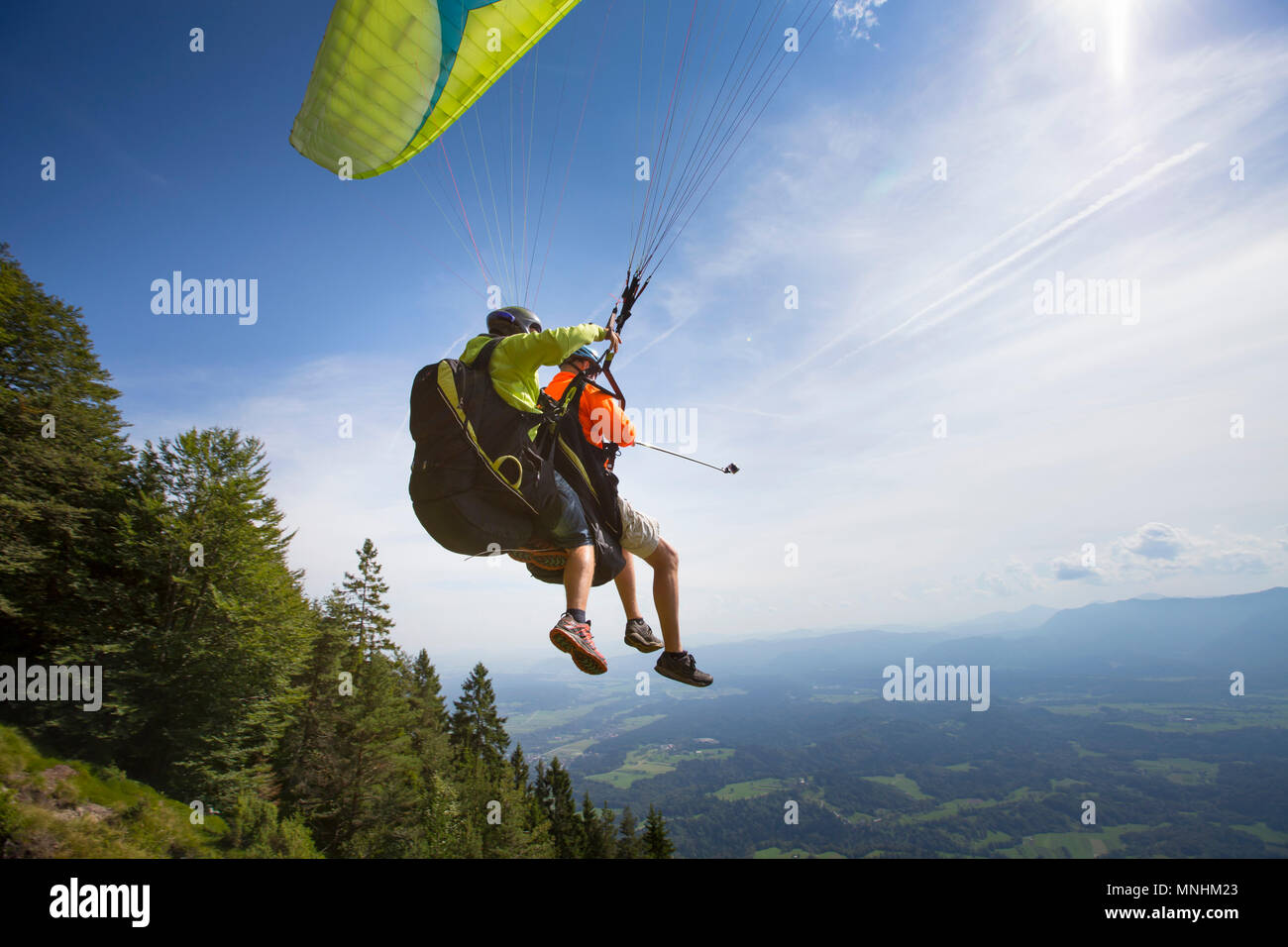 Due parapendio in tandem sono il decollo dalla montagna Dobrca. Uno è in possesso di un bastone selfie con azione fotocamera, vicino a Begunje e Radovljica, Alta Carniola, Slovenia Foto Stock