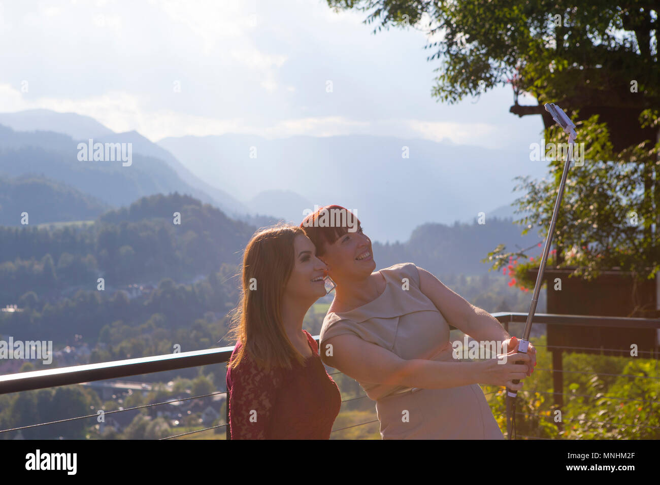 Sorridente due giovani donne tenendo selfie con selfie stick a Radovljica, Alta Carniola, Slovenia Foto Stock