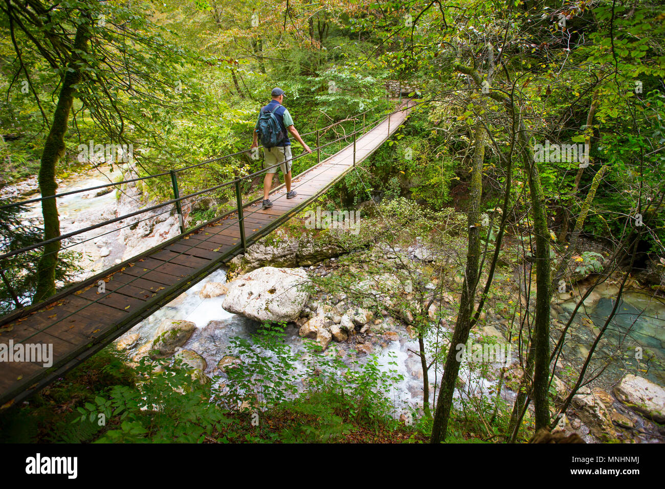 Maschio singolo incrocio backpacker passerella in legno di Tolmino gorge nel Parco Nazionale del Triglav, Slovenia Foto Stock