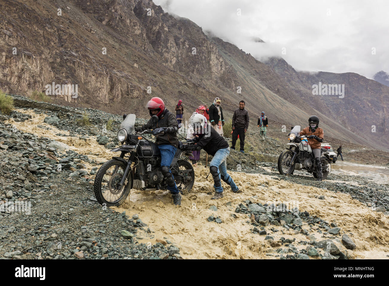 Valle di Nubra, India - 29 Giugno 2017: motociclisti che si aiutano reciprocamente per attraversare il fiume che scorre dalla fusione di neve in Himalaya, regione del Ladakh, indi Foto Stock