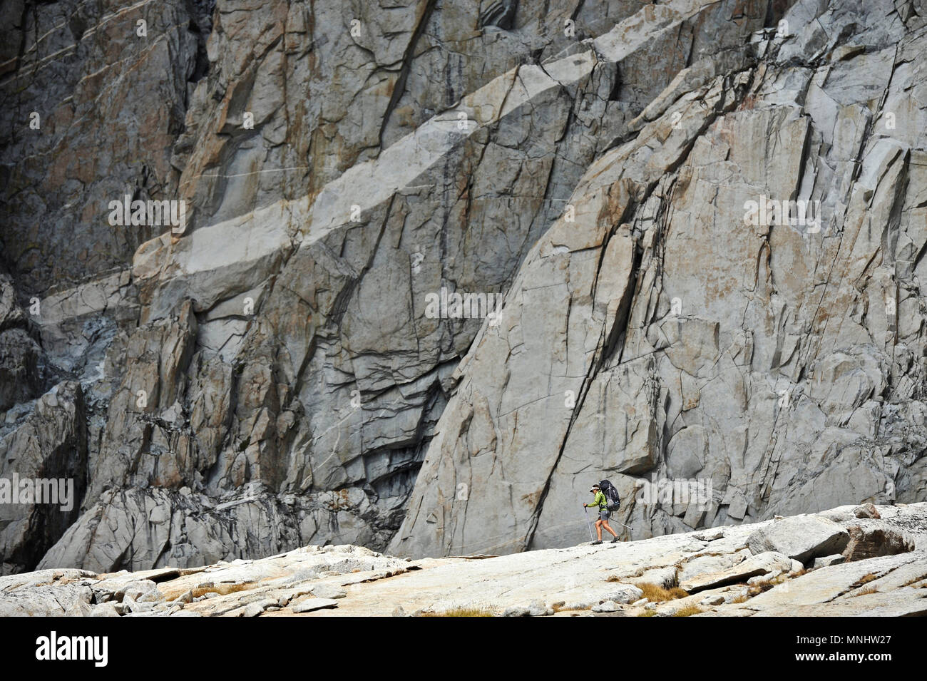 Escursioni per Backpacker sotto una parete di granito nel bacino di palizzata su una di due settimane trek della Sierra Alta Via in Kings Canyon National Park in California. Il 200-miglio percorso circa parallels il famoso John Muir Trail attraverso la Sierra Nevada gamma di California dal Kings Canyon National Park Parco Nazionale di Yosemite. Foto Stock