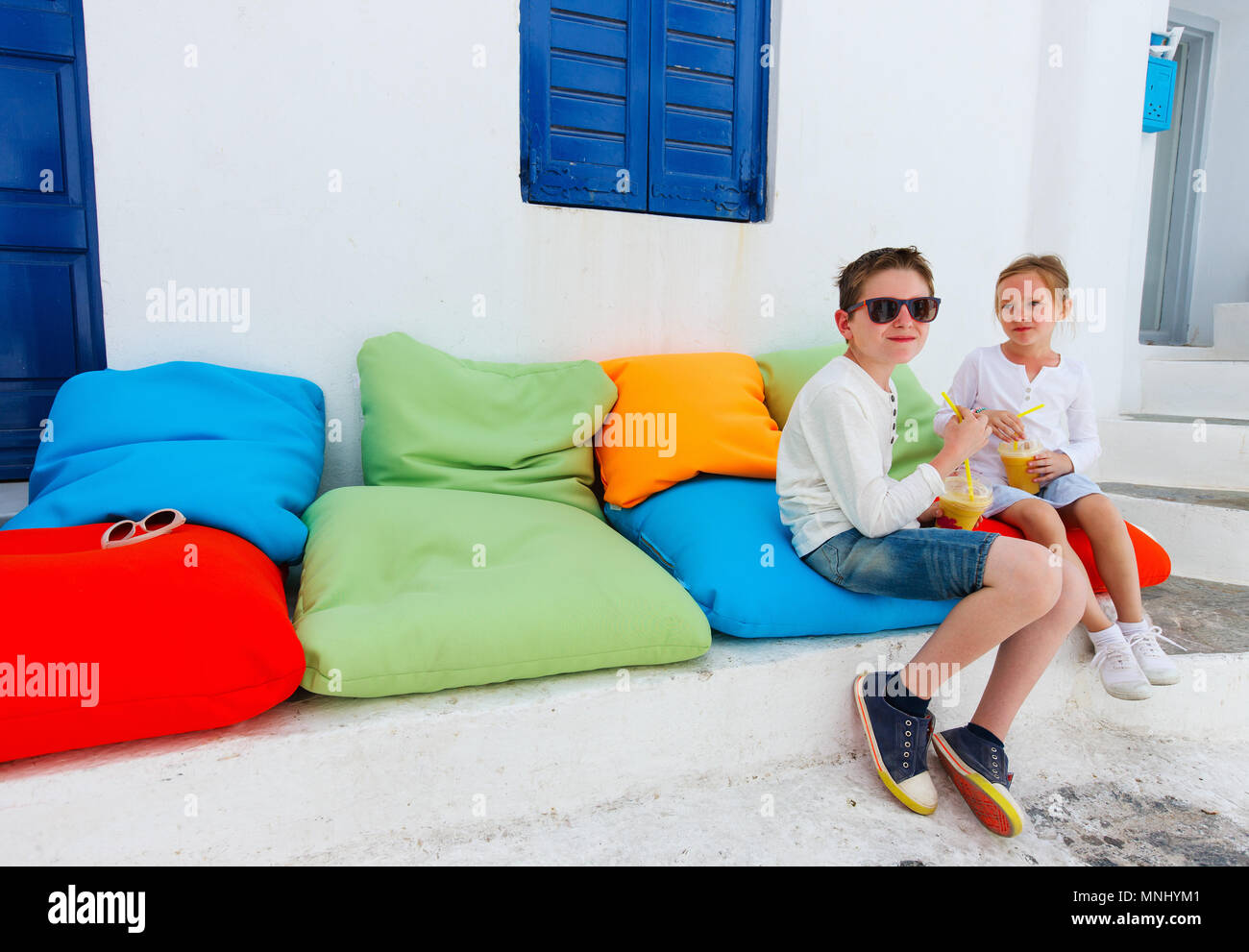 Due simpatici ragazzi del fratello e sorella di bere freschi frullati in un colorato cuscini a outdoor cafe sul giorno di estate Foto Stock