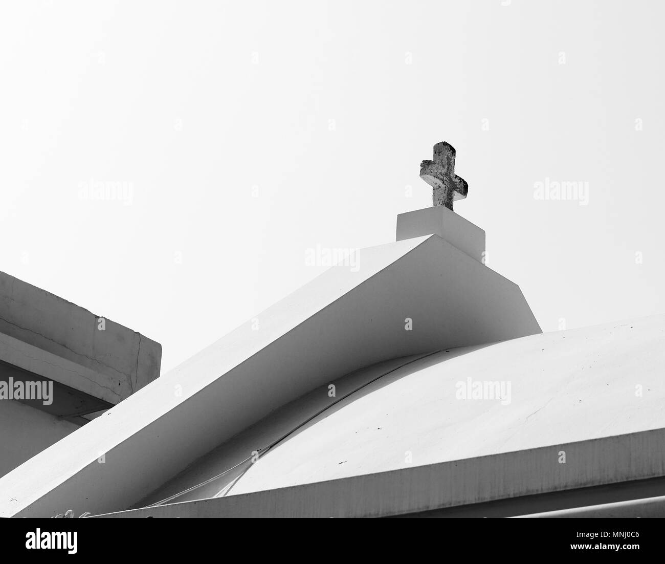 Parte del tetto con una croce contro il cielo in bianco e nero Foto Stock