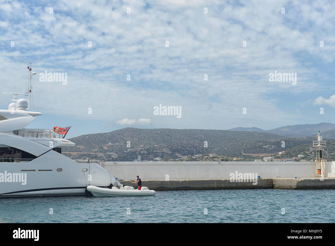 Parte di un grande yacht e barca sul molo contro il cielo e le montagne Foto Stock