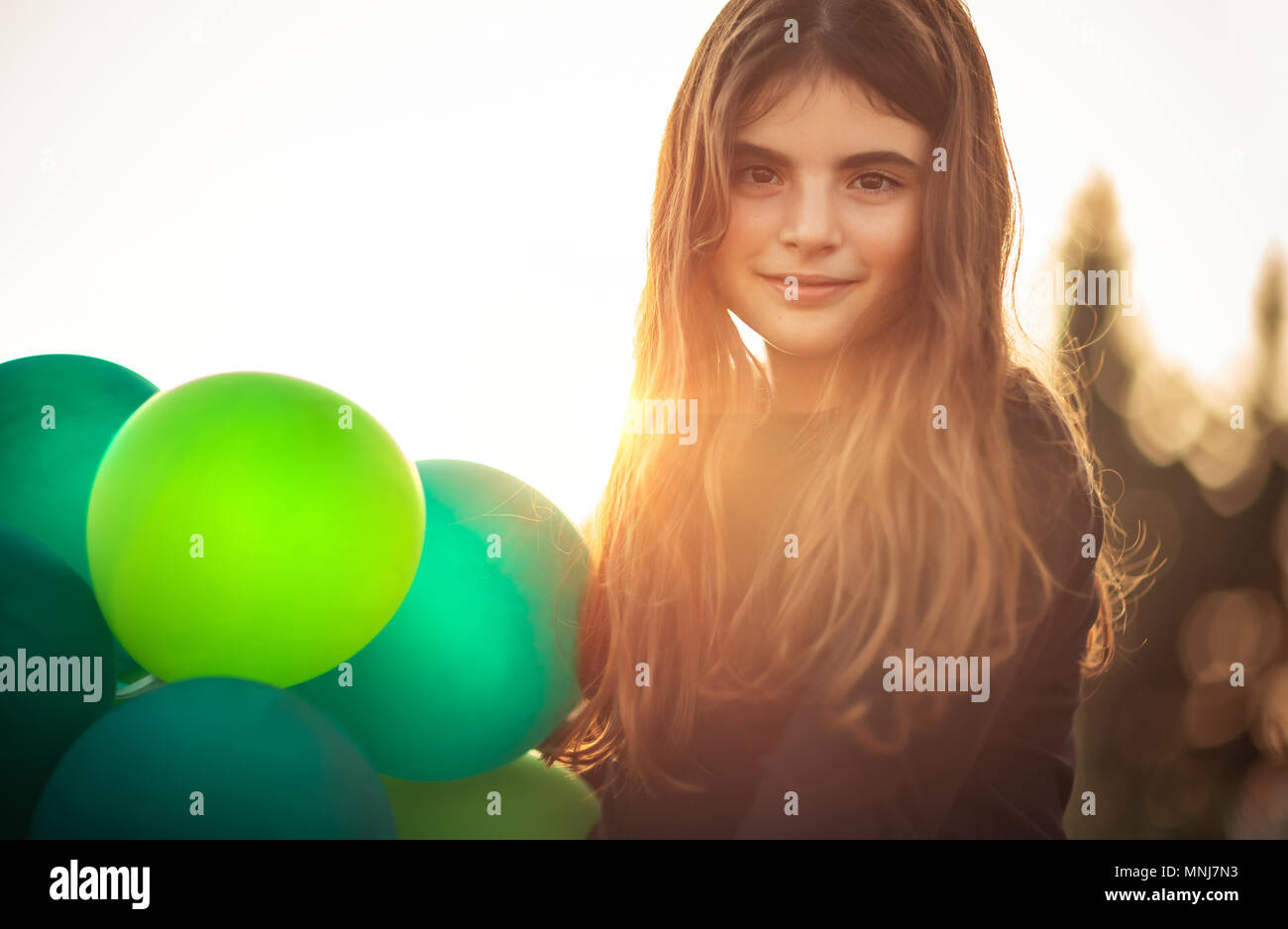Ritratto di una ragazza carina con aria palloncini all'aperto in serata dolce della luce del sole, festeggia il compleanno, vacanze e concetto di divertimento Foto Stock