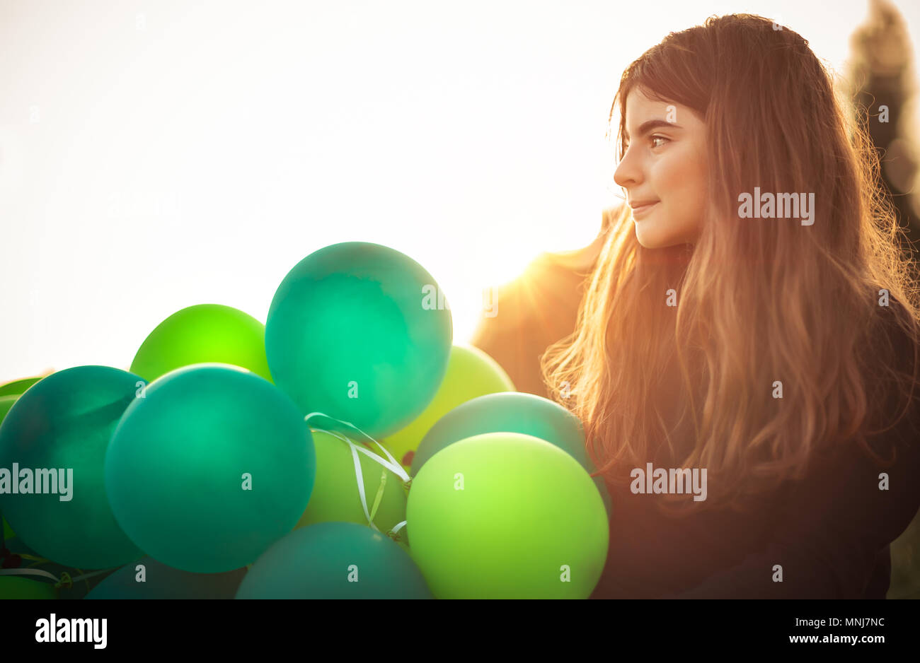 Ritratto di una ragazza carina all aperto con grande pila di aria verde palloncini, si prepara a celebrare la festa di compleanno, felice infanzia spensierata Foto Stock