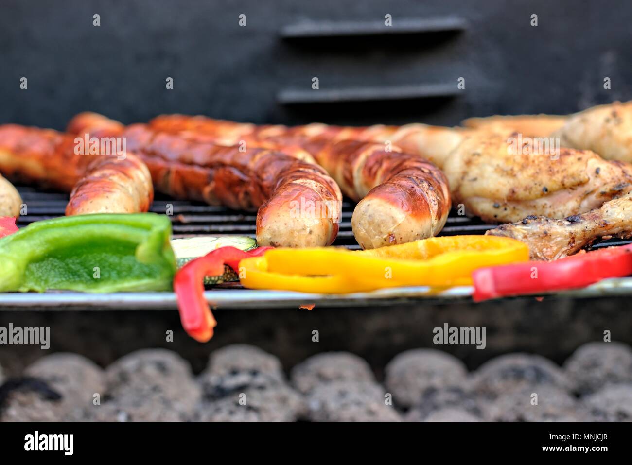 Il cibo era gustoso, nutrizione, della cucina e del barbecue concetto: salsicce alla griglia,coscia di pollo e verdure su un barbeque. Foto Stock