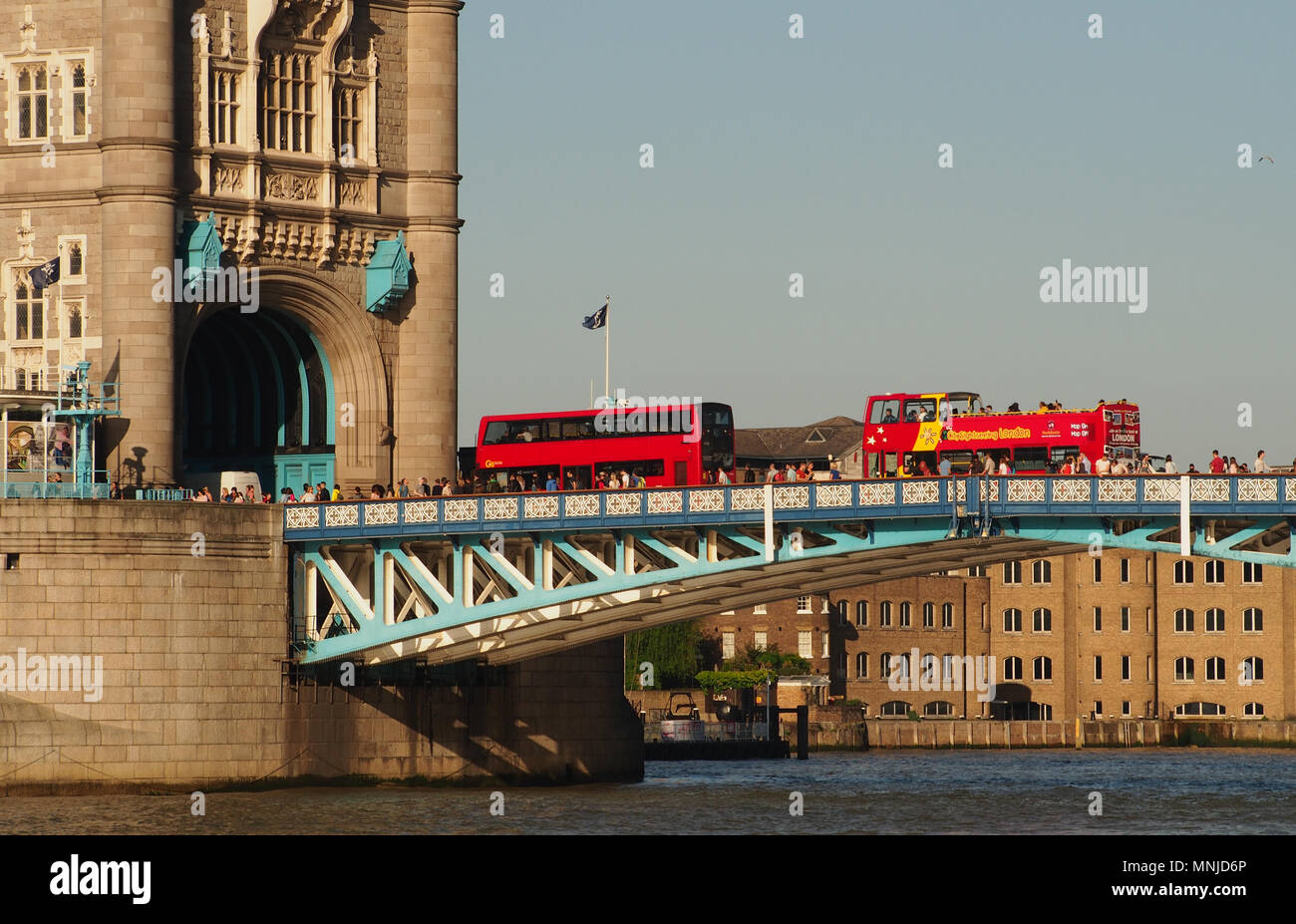 Una vista di due autobus di Londra, una parte superiore aperta, e pedoni andando oltre il Tower Bridge di Londra con una vista del fiume Tamigi al di sotto di Foto Stock