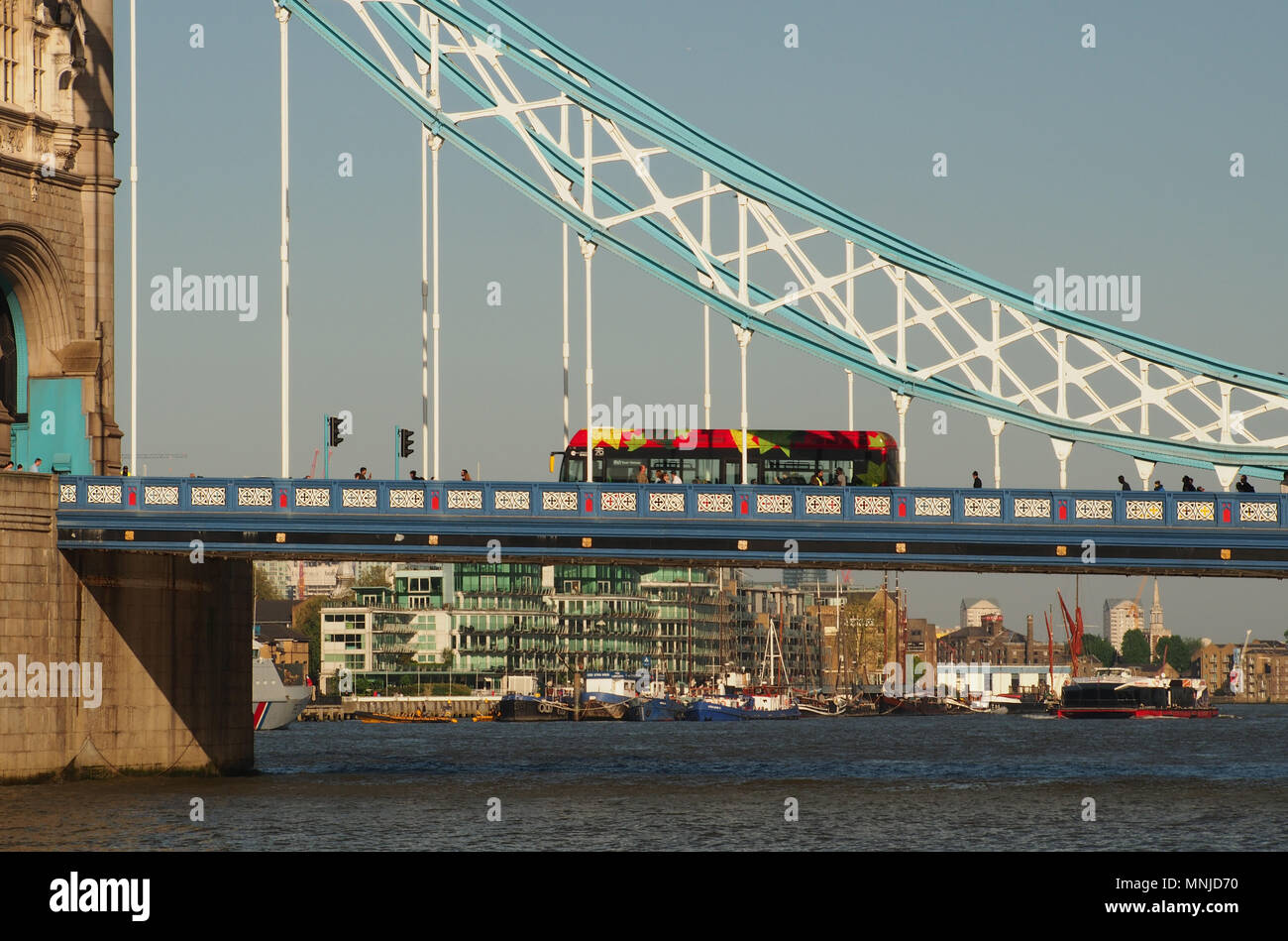 Una vista di un bus londinese e pedoni andando oltre il Tower Bridge di Londra con una vista del fiume Tamigi e barche al di sotto di Foto Stock