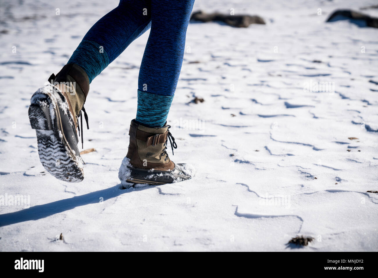 Sezione bassa della donna in stivali a piedi attraverso la neve Foto Stock