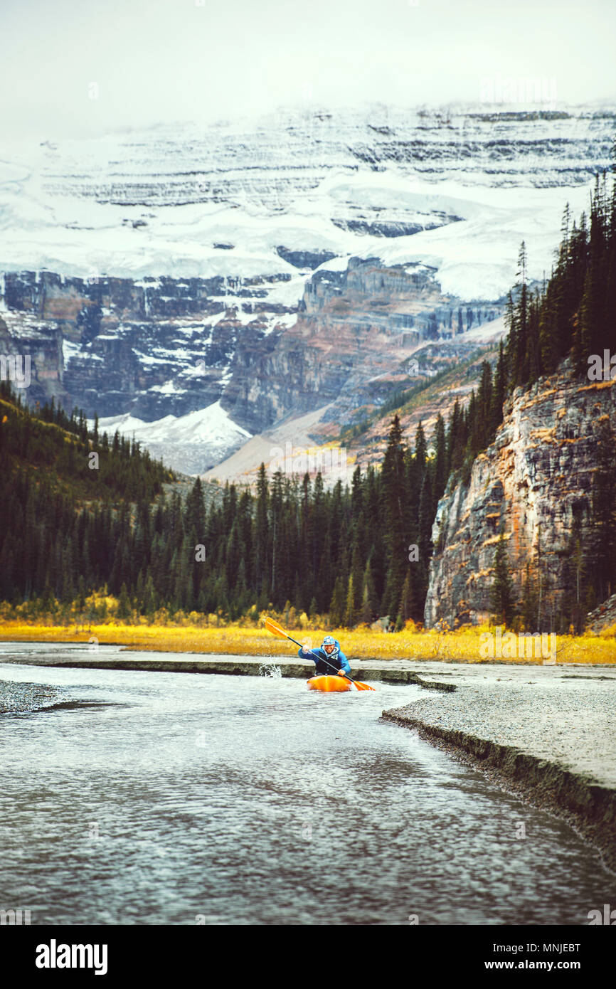 Vista in lontananza kayaker sguazzare nel flusso vicino al Lago Louise con il Monte Victoria in background, il Parco Nazionale di Banff, Alberta, Canada Foto Stock